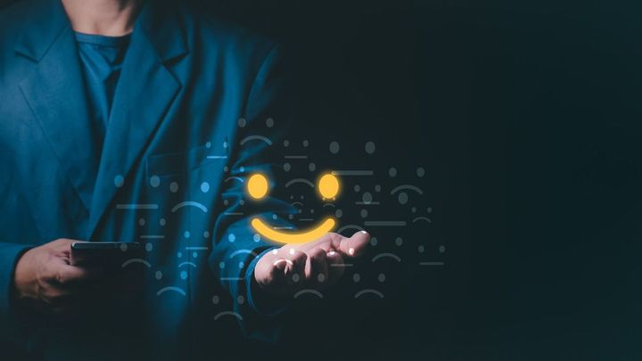 ビジネスマンの手のひらに乗った笑顔のアイコン
