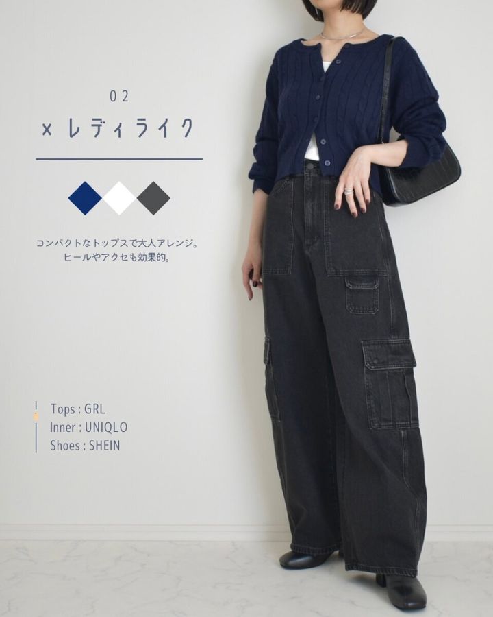 黒いバレルユーティリティジーンズとネイビーのカーディガンを着用し、黒いハンドバッグを持つ女性の全身