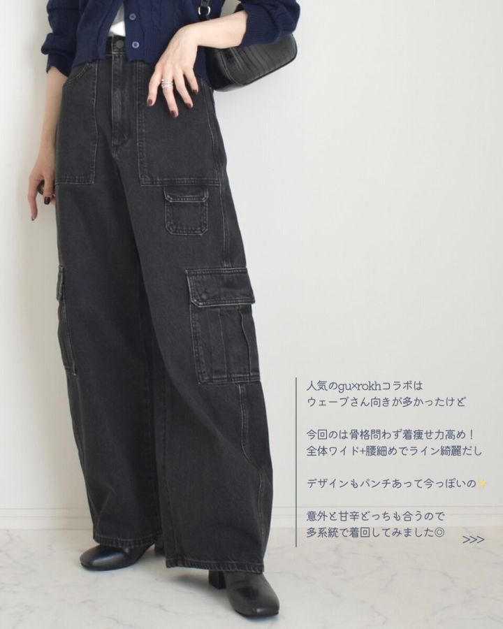 黒いバレルユーティリティジーンズとネイビーのカーディガンを着用し、黒いバッグを持つ女性の全身