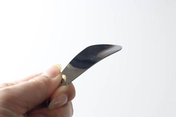 指でつまんで持ったステンレスミニ靴ベラの緩やかなカーブ部分