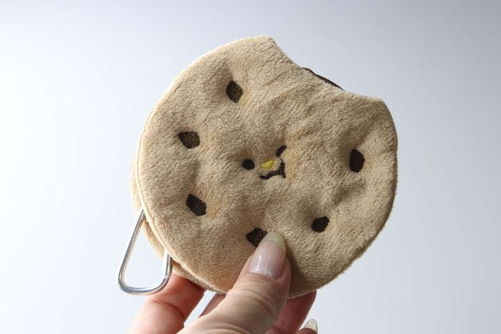 女性の指がクッキー型ポーチのカラビナ部分を持ち、ポーチの表面を見せている