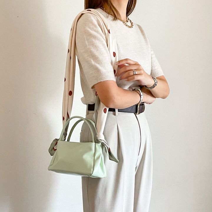白半袖ニットとベージュパンツの女性がドット柄スカーフをバッグのショルダーにする
