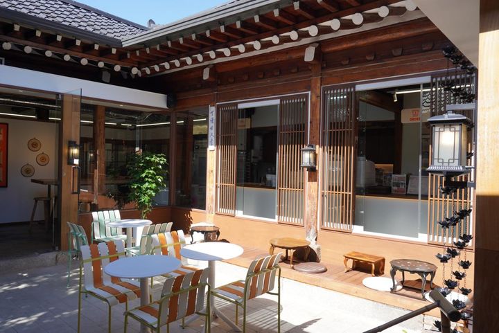 韓屋の風情を感じる空間に、カラフルなチェアやテーブルが並ぶマダン（中庭）席。昔ながらの趣きとモダンな雰囲気が調和した、心地よい空間です。