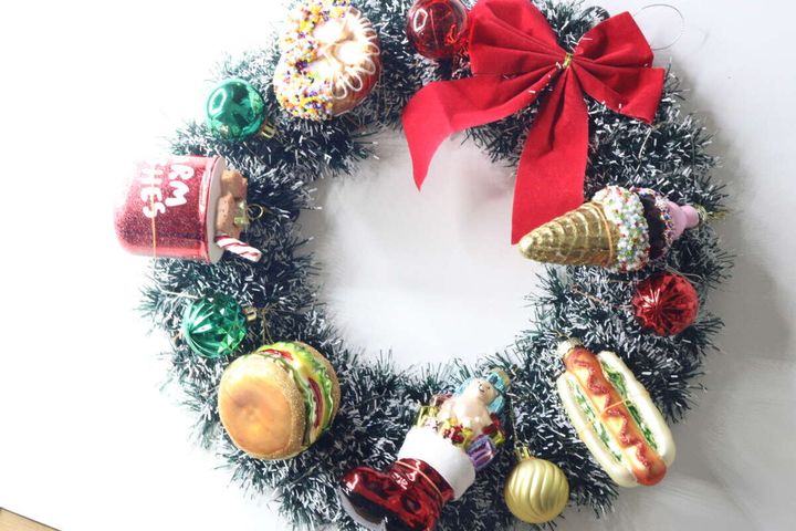 緑のモールのクリスマスリースに様々な種類の食べ物モチーフのオーナメントを飾り付けた状態