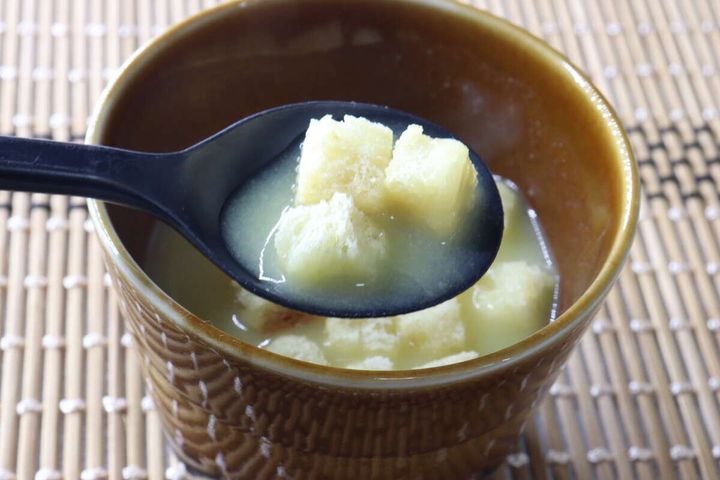 黒いスプーンで、スープとクルトンをすくっている様子