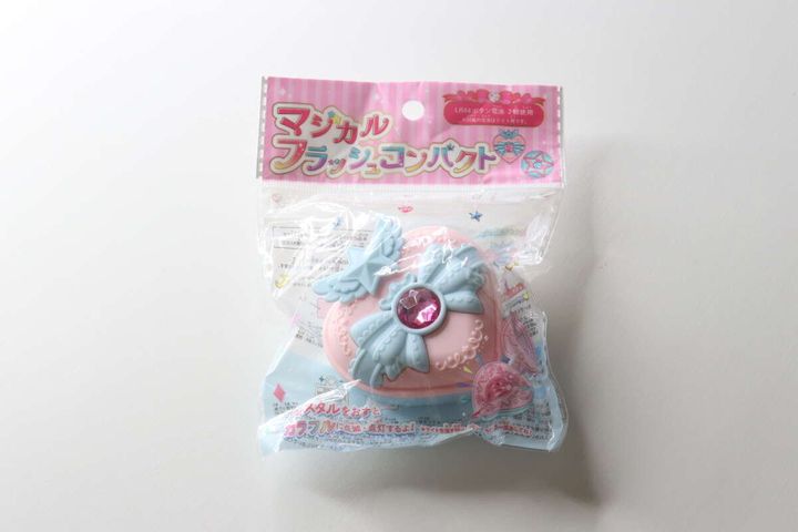 ピンクと水色のストライプ柄のパッケージに入った、ハート型のマジカルフラッシュコンパクト