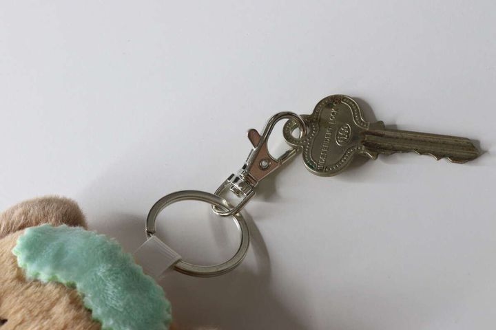 白い背景に、キーホルダーの金具部分に鍵が1本取り付けられている様子