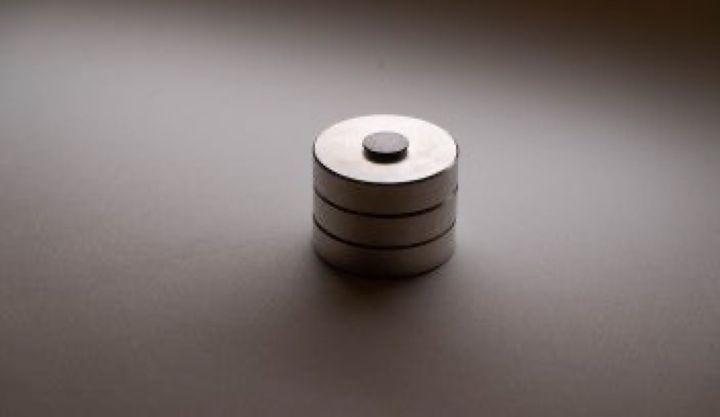3つ重ねた円形の磁石の上に浮かぶ、黒いグラファイト(黒鉛)の円盤です。同じ OIST が別の研究で発表した、電源のいらない浮遊台です。
