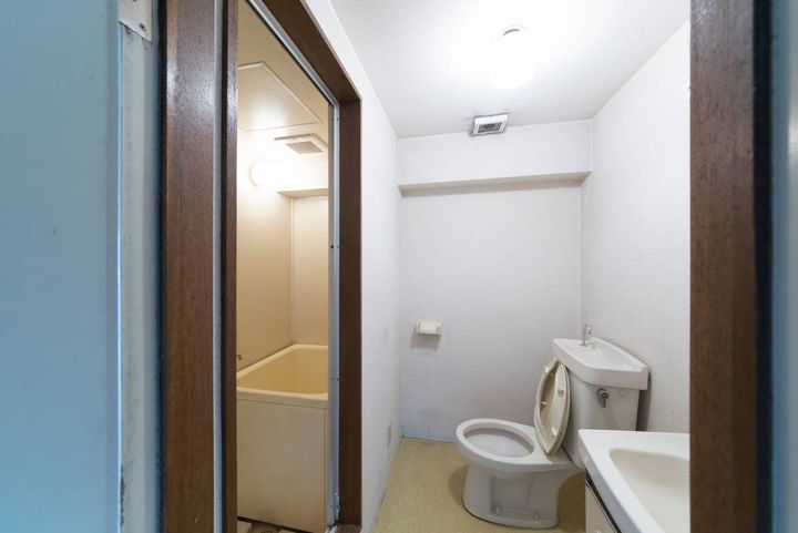 トイレと洗面台がある水回りの室内。左側の開いた扉の奥に浴室が見える。
