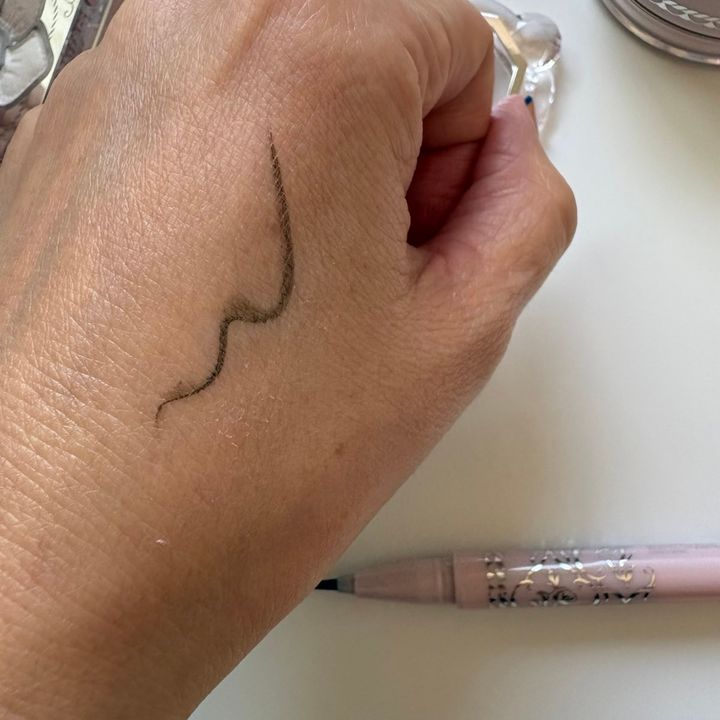 手の甲に描いた限定アイライナーのスウォッチ。肌なじみの良い繊細なグレイッシュブラウンのラインです。