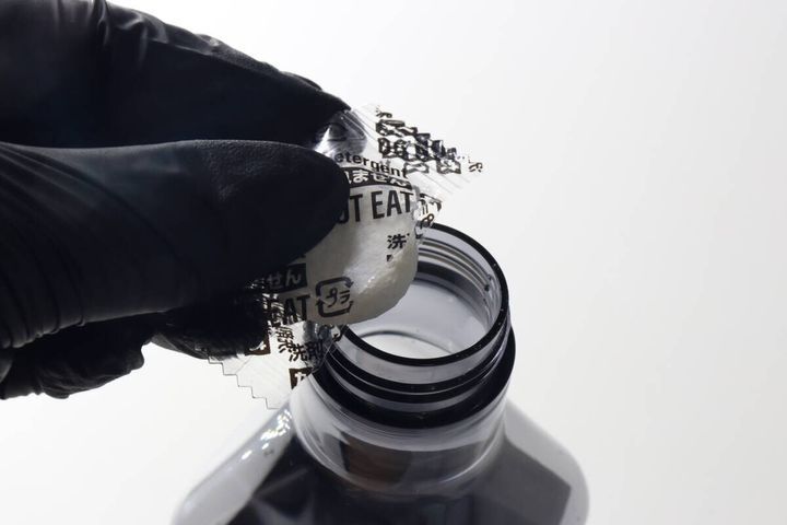 黒い手袋をした手で錠剤をスプレーボトルに入れている瞬間