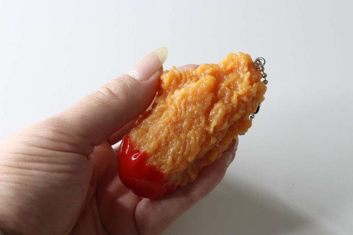 手のひらでフライドチキンキーホルダーを握るように持っている様子