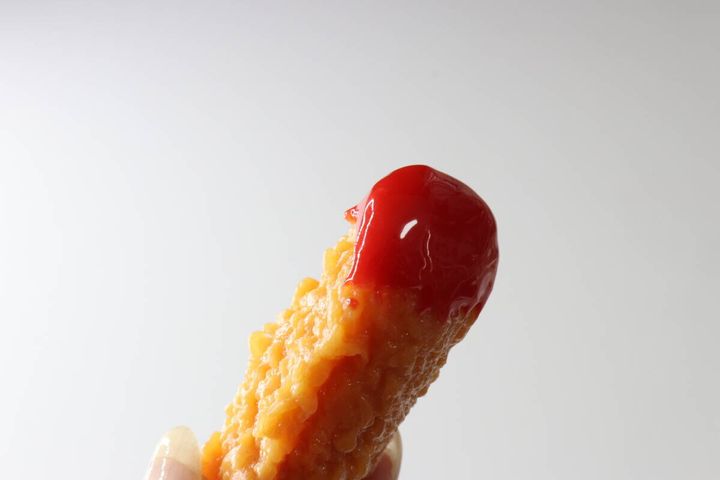 指でつまんだフライドチキンキーホルダーの赤いソース部分の接写