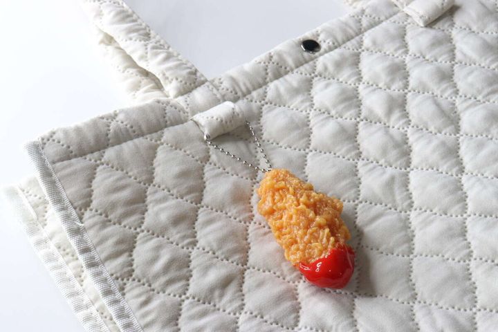 白いキルティングバッグにフライドチキンキーホルダーが付いている様子