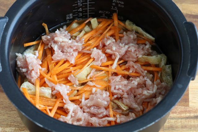 炊飯器に鶏ひき肉、油揚げ、にんじんをのせる