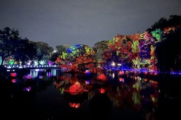 池の背後にある木々をスクリーンに絵巻物が展開される