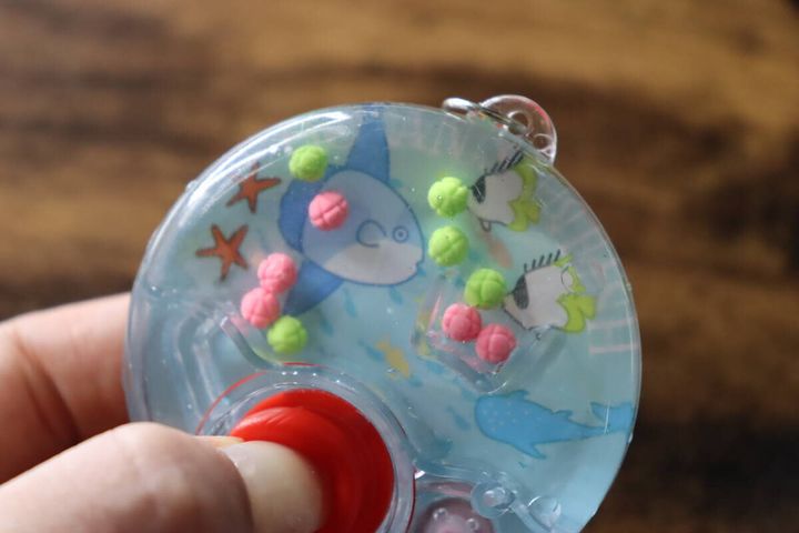 中に水とカラフルなボールが入ったゲーム機を操作する様子