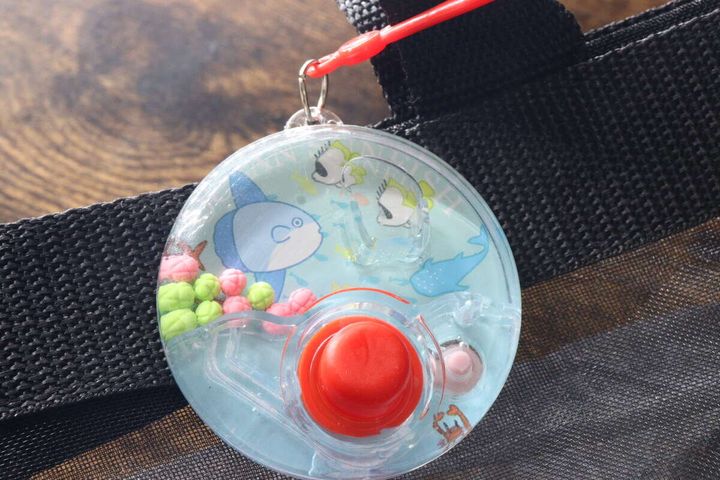 黒いバッグの持ち手にキーホルダーで取り付けられたゲーム機