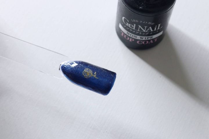 トップコートのボトルとフィルムを貼り終えたネイルチップの俯瞰写真