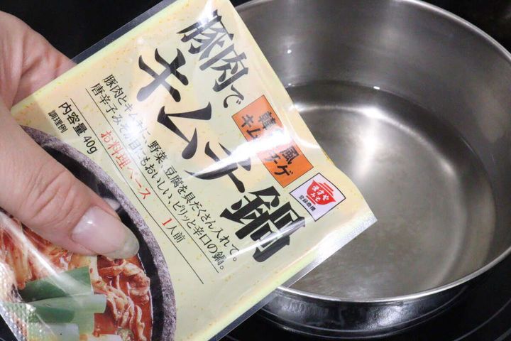 シルバーの鍋にキムチ鍋の素のパッケージをかざしている様子