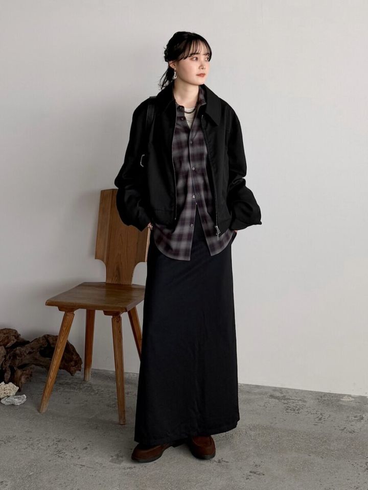 黒のブルゾンとロングスカートのシックな装いにチェックシャツをインしたスタイル