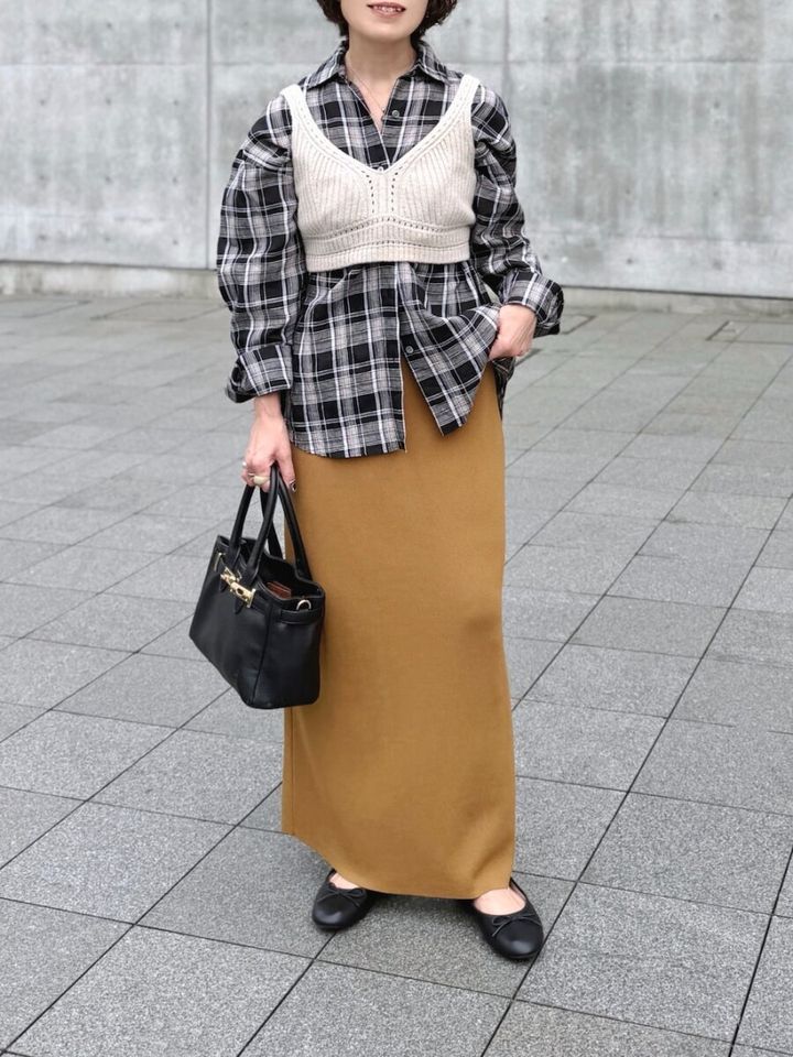 チェックシャツに白のニットビスチェとキャメル色のタイトスカートを合わせた着こなし