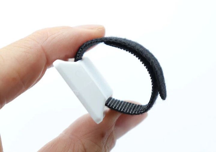 指で持った白い粘着フックと黒い面ファスナーのベルト付コードフック