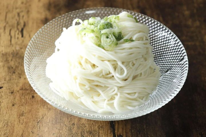 ガラスの器に盛られた冷やしそうめん、刻みネギが乗っている