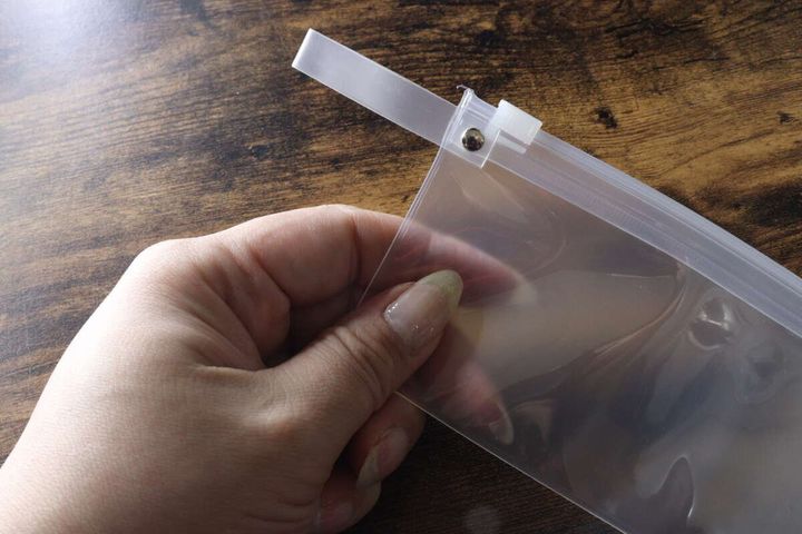 ポーチのジッパー部分としっかり留められたループの金具を指で持っている様子