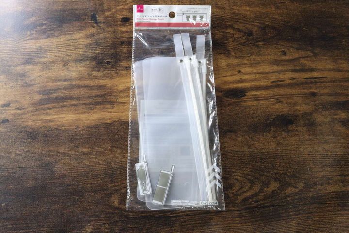 木目のテーブルの上に置かれたダイソーのミニマスコット収納ポーチのパッケージ