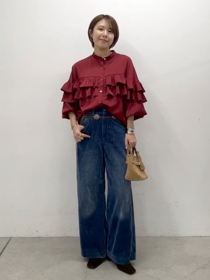 深みレッドのフリルブラウスにブルーのワイドデニムのコーデ