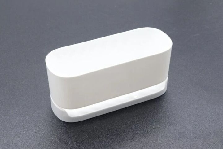 白い長方形のスポンジ＆洗剤ホルダーが黒い背景に置かれている