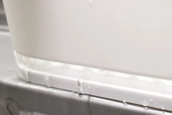白いスポンジ＆洗剤ホルダーの底から水が流れ落ちる様子をクローズアップ