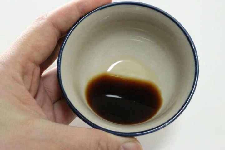 手で持った白い小鉢の底に黒っぽいバルサミコ酢が少量入っている