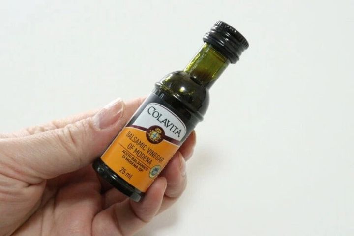 手で持っている小さな「コラビータ バルサミコ酢 モデナ」のボトル