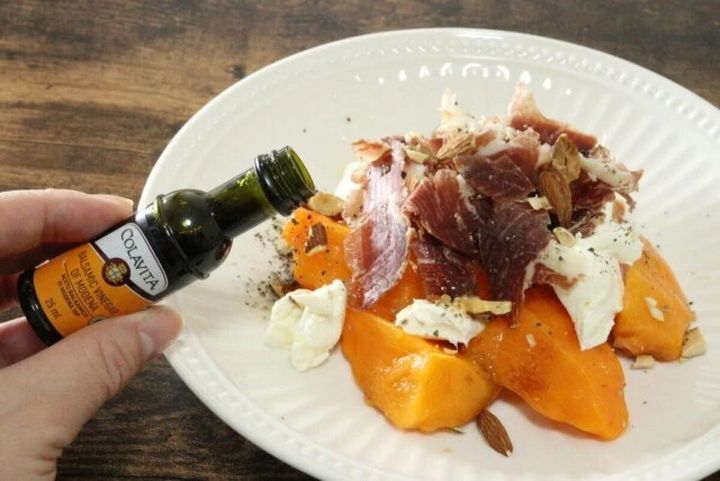 柿と生ハムとチーズのカプレーゼにバルサミコ酢をかけている