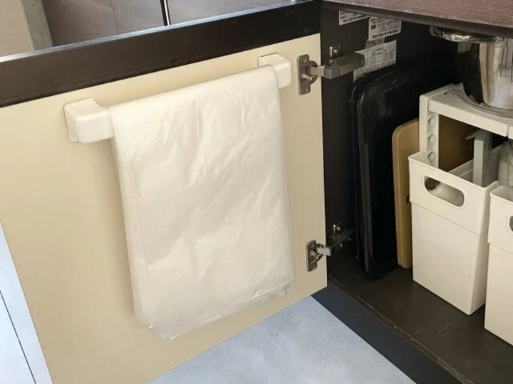 キッチンの開き戸の裏側にタオルバーを取り付けゴミ袋を掛けている様子