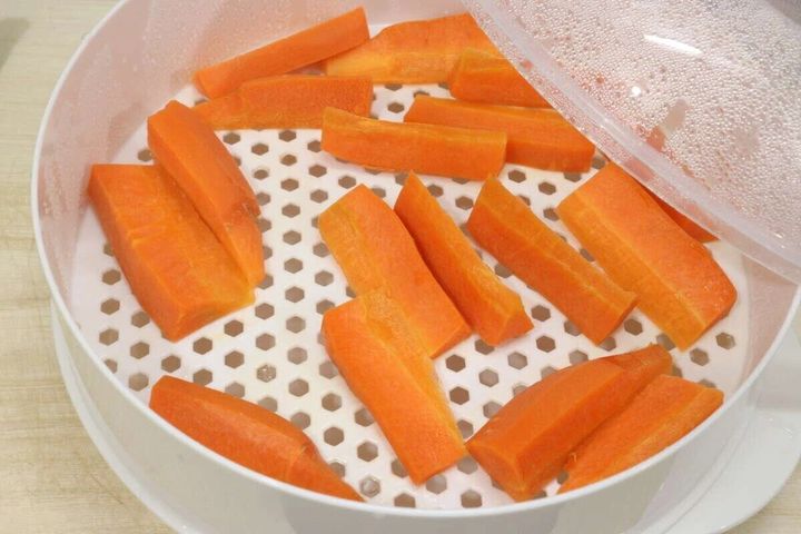 蒸し器のざるの上にスティック状に切られたニンジンが並んでいる状態