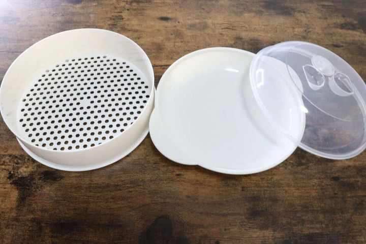 白いざるプレートと受け皿、透明なドーム型のフタが並んだ蒸し器