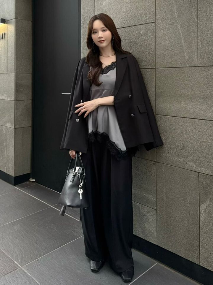 黒ジャケットを肩掛けしレースインナーを合わせた女性の写真