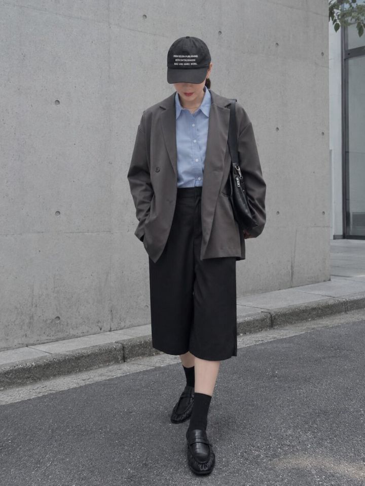 キャップとハーフパンツにジャケットを合わせた女性の全身写真