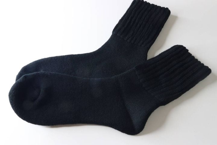 白い背景に並べられた黒い裏起毛パイルソックス2足。