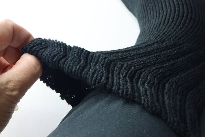 足に履いた黒い靴下の履き口を指で引っ張り、伸縮性とゆったり感を確かめている。