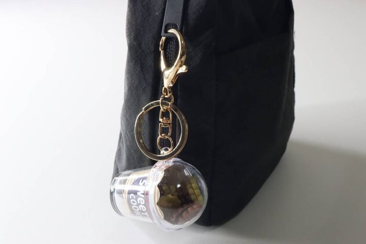 黒いバッグの持ち手にゴールドの金具で取り付けられたキーホルダー