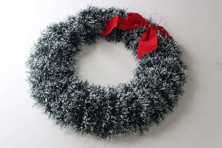緑と白のモールでできたクリスマスリース。上部に赤いリボンと吊り下げ用の白い紐が付いている。