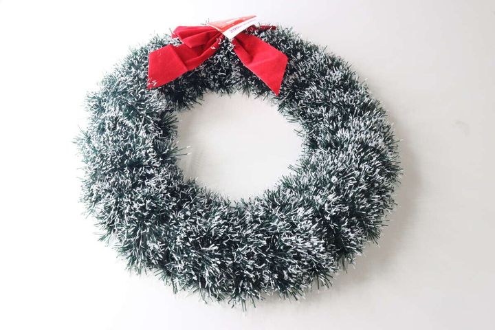 緑と白のモールでできたクリスマスリース。上部に赤いリボンが飾られている。