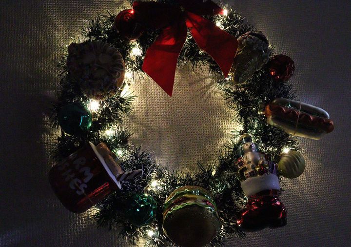 クリスマスリースにオーナメントとライトをつけて飾っている様子