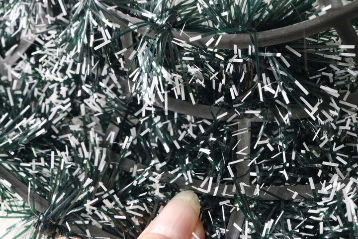 クリスマスリースのモールのアップ。指でモールの骨組み部分を触り、作りを確認している。