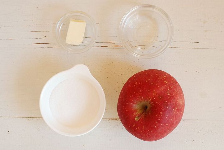 白い木目を背景にキャラメルりんごの材料である丸ごとのリンゴと調味料が並べられた俯瞰写真