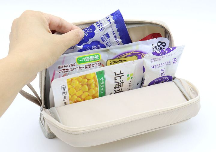女性の指が、ポーチに収納されたレトルト食品を取り出そうとしている